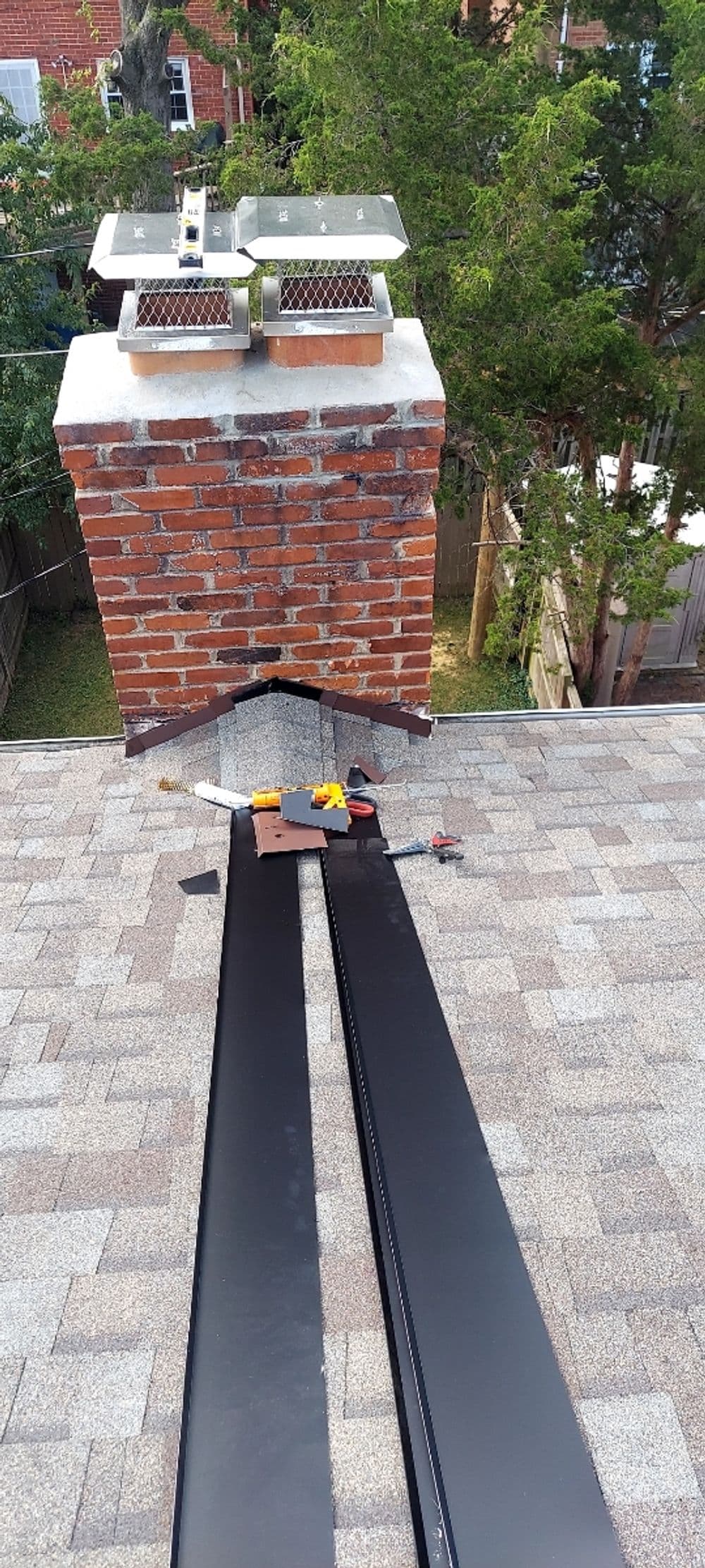 Chimney on a rooftop with solar vents and roofing materials for repair or installation.