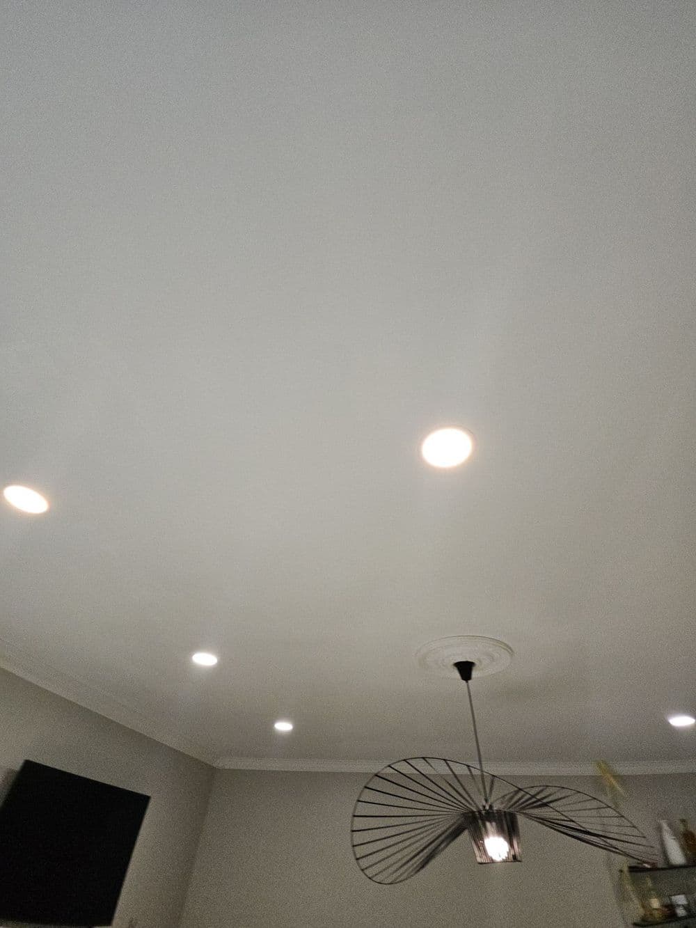 Modern ceiling design with recessed lights and a stylish pendant lamp in a living room.