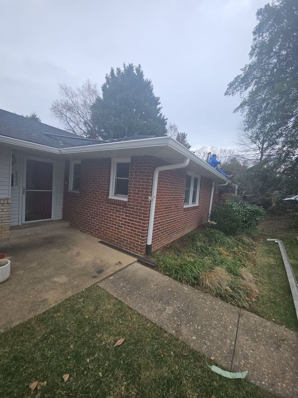 Brick house exterior with side view, featuring a sloped roof and well-maintained landscaping.