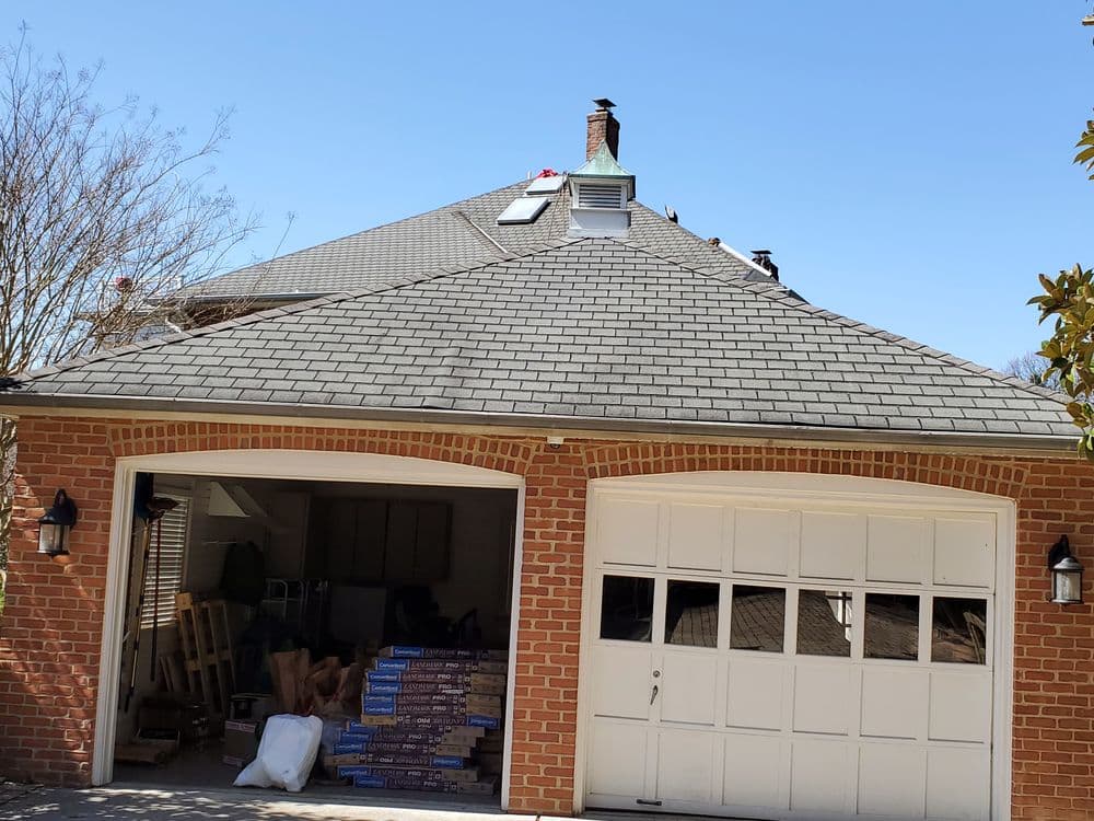 Two-car garage with brick facade and packed items, under a clear blue sky.