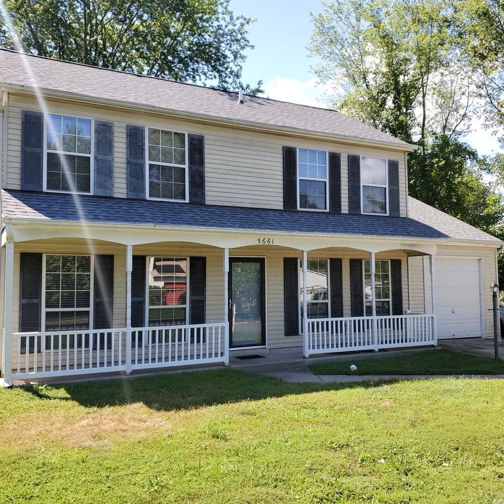 Two-story home with gray shingles, white siding, and a front porch at 5661. Lush green yard.