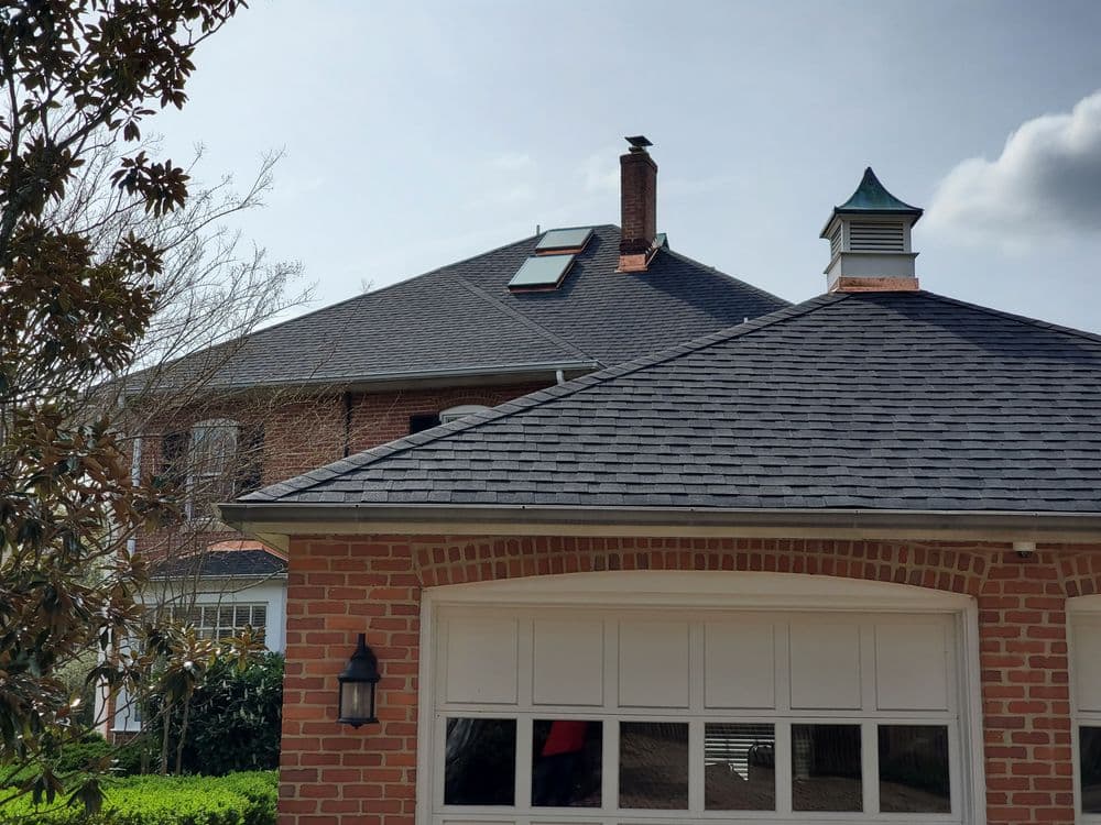Brick house with a gabled roof, skylight, and chimney under a clear sky.