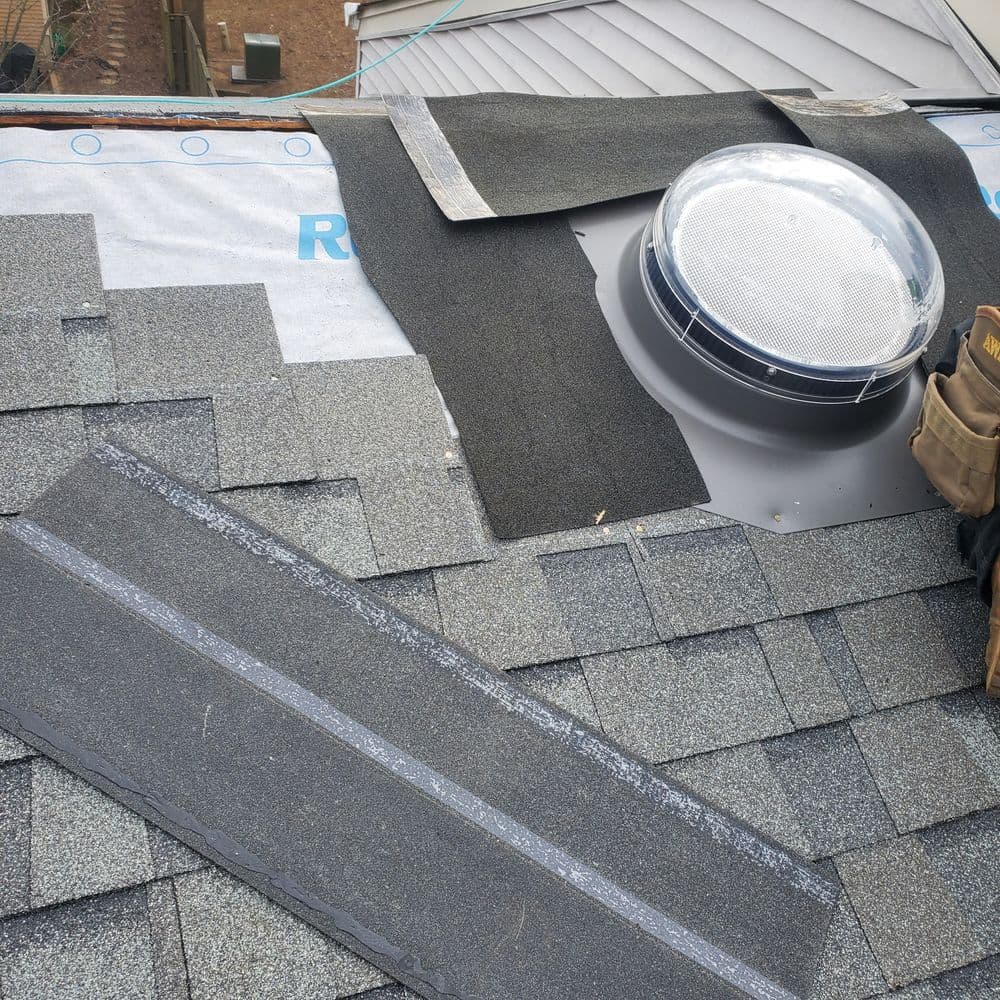 Newly installed roof with shingles and a skylight, showcasing roofing materials and craftsmanship.